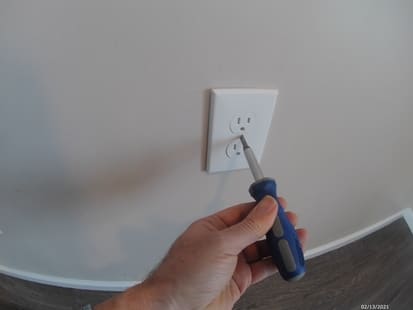 photo of screw driver removing a outlet faceplate