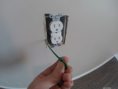 photo of a plastic coffee stir stick being inserted along side of a outlet box