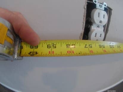 photo of using a tape measure next to the outlet box