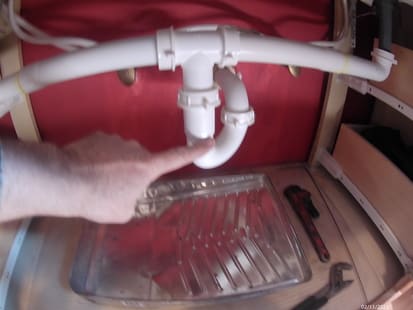 photo of a finger pointing to a pipe  trap under a sink