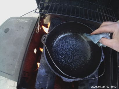 photo of coating chicken fat on a cast iron pot for seasonong