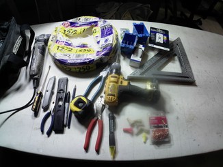 a picture of a table with wire, drill, tape measure, square, marker, utility knife and other tools